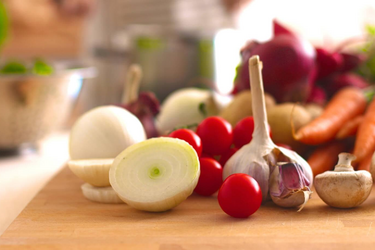 Frisches Gemüse auf einem Holzbrett - Zwiebel, Knoblauch, Tomaten, Frühlingszwiebel, Karotten