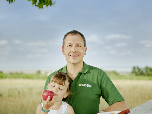adeg Kaufmann Wolfgang Stadlmann mit seiner Tochter die gerade einen Apfel isst
