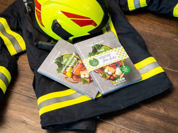 Adeg Kochbuch auf Feuerwehrjacke und Helm
